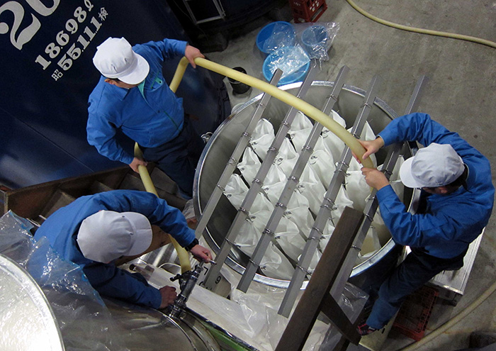 Daiginjo sake being pressed in traditional cloth bags.